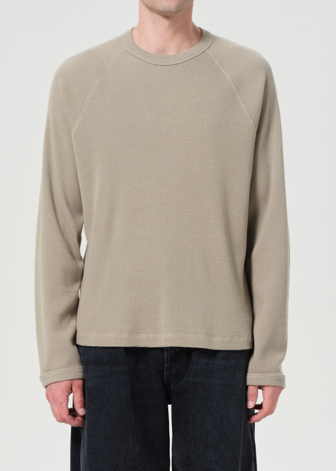Beige long-sleeve shirt worn by a person on a plain background
