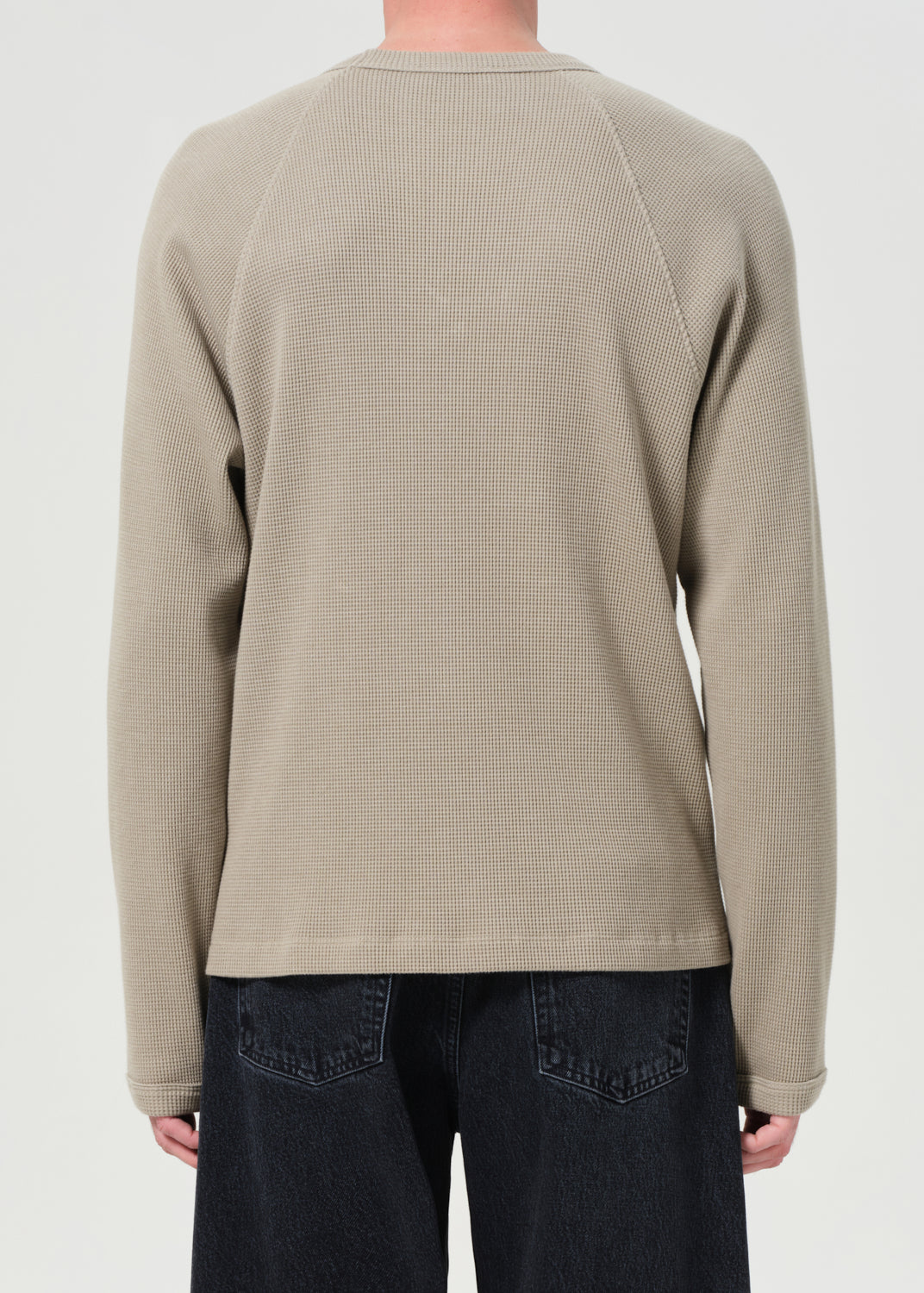 Person wearing a beige textured sweater on a plain background