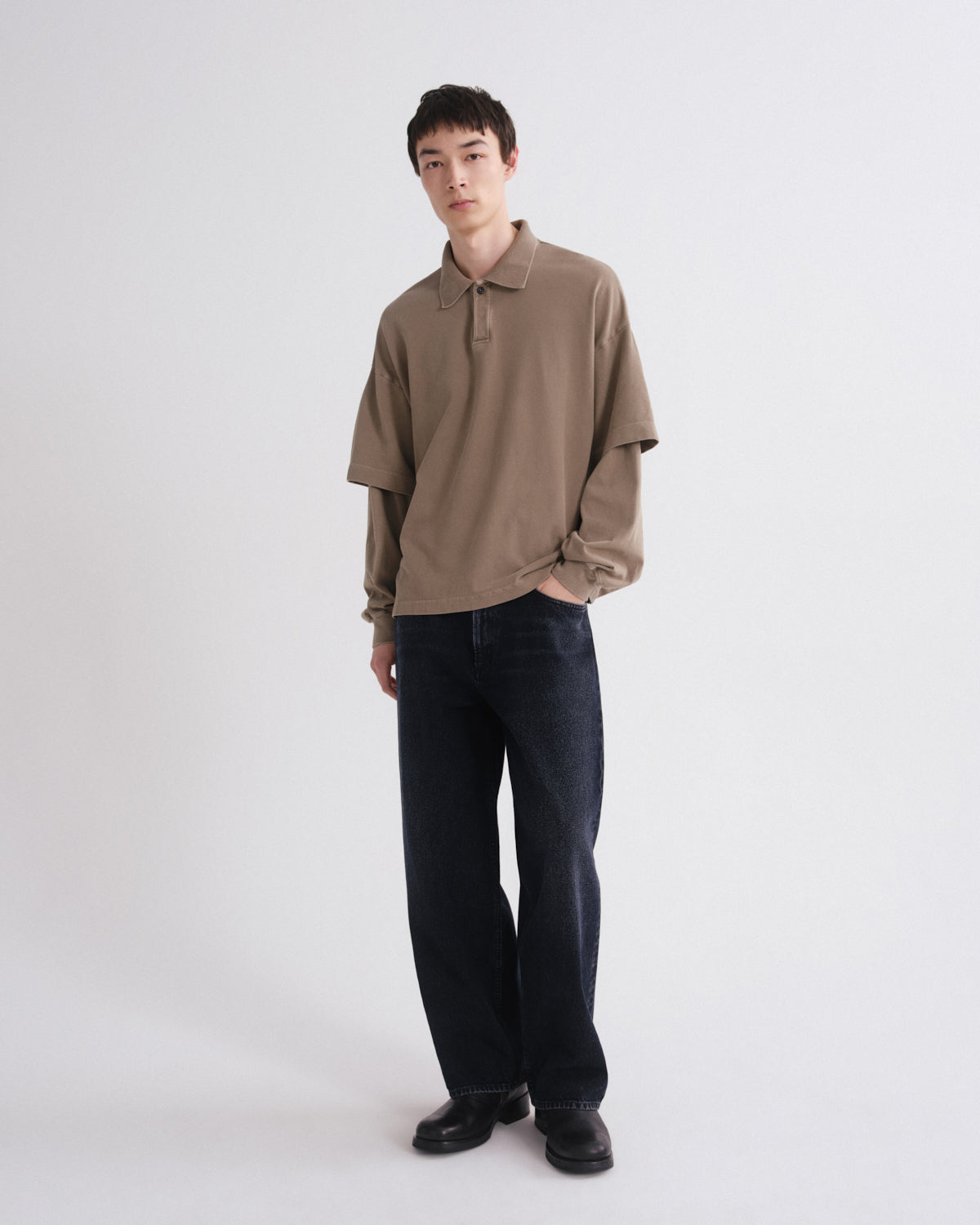 Person wearing a brown polo shirt and black pants on a white background
