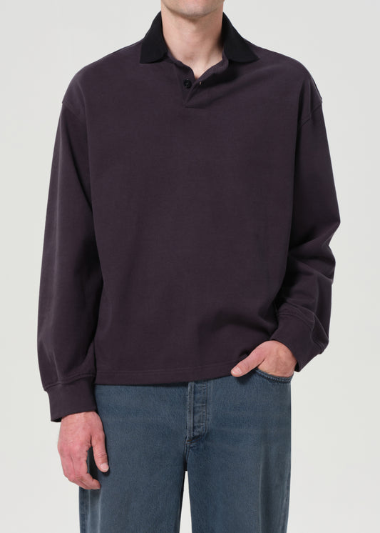 Person wearing a dark purple sweater and blue jeans on a light gray background