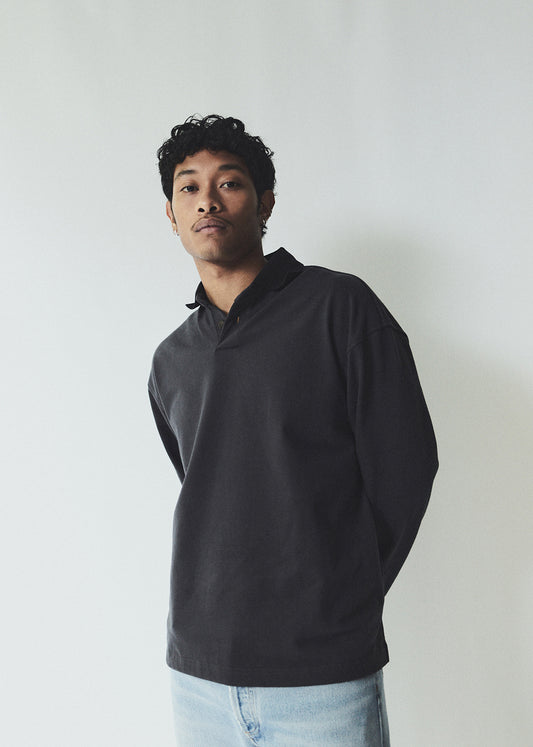 Man wearing a black hoodie and light blue jeans against a white background