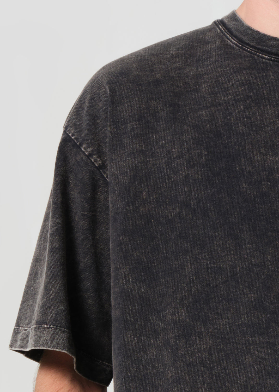 Black t-shirt worn by a person on a light gray background