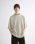 Person wearing a light beige oversized T-shirt with dark pants, front view