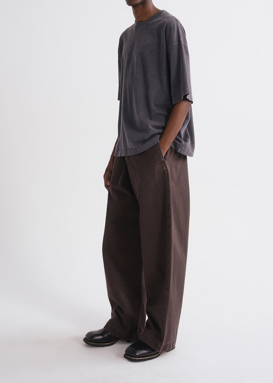 Person wearing a grey shirt and brown pants on a grey background