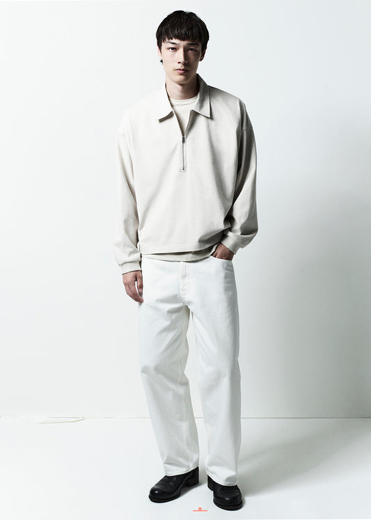 Person wearing a light-colored sweater and white pants on a white background