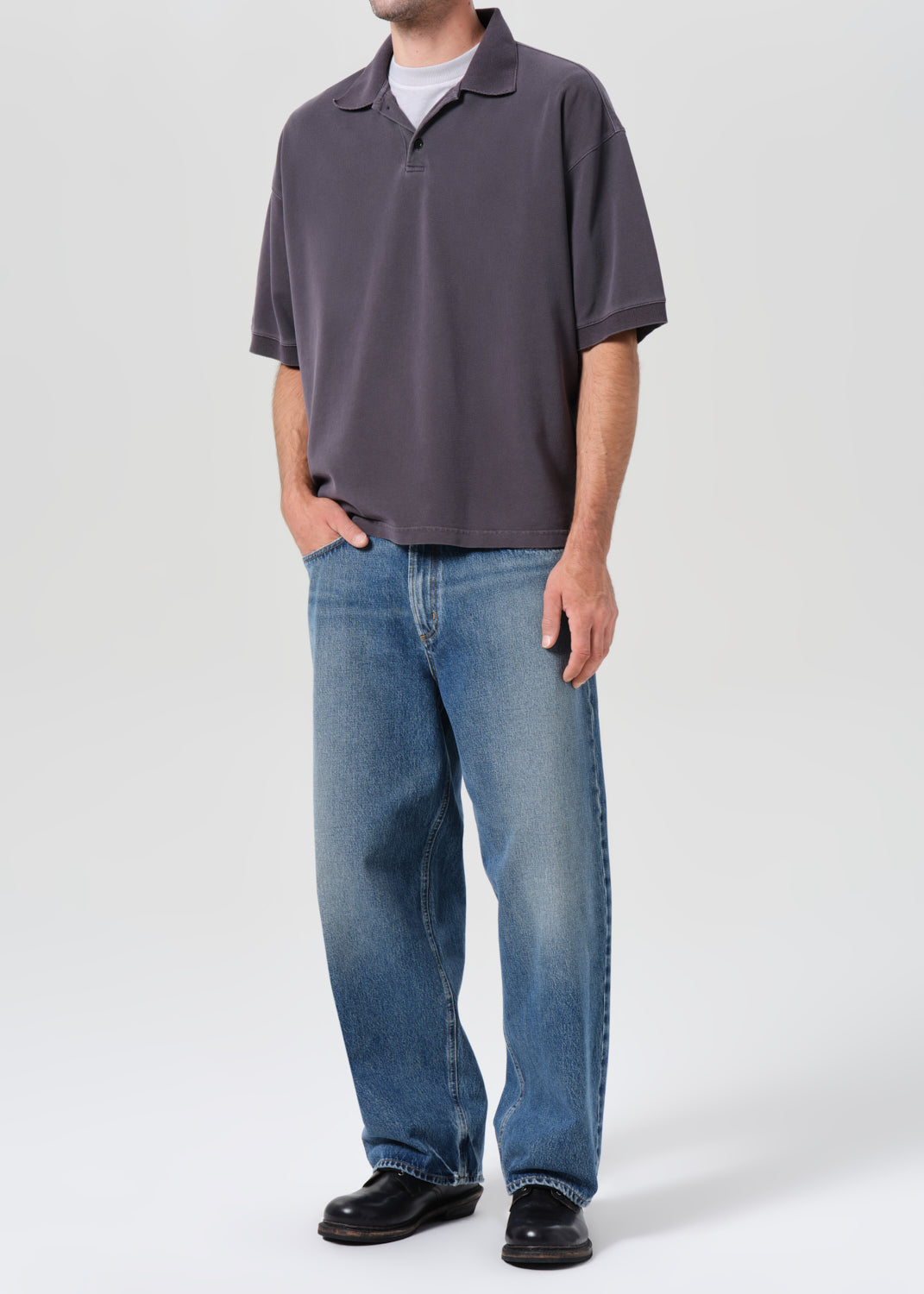 Person wearing a gray polo shirt and blue jeans on a white background