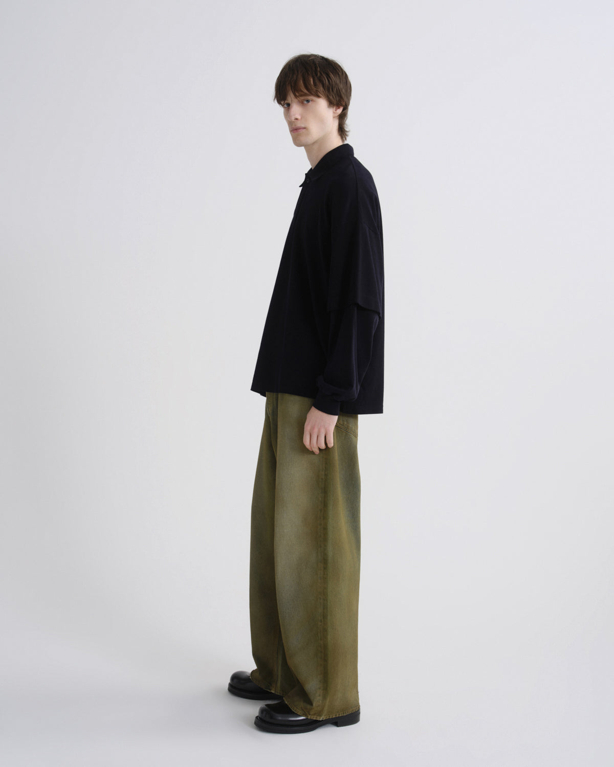 Person wearing a black jacket and green pants on a white background