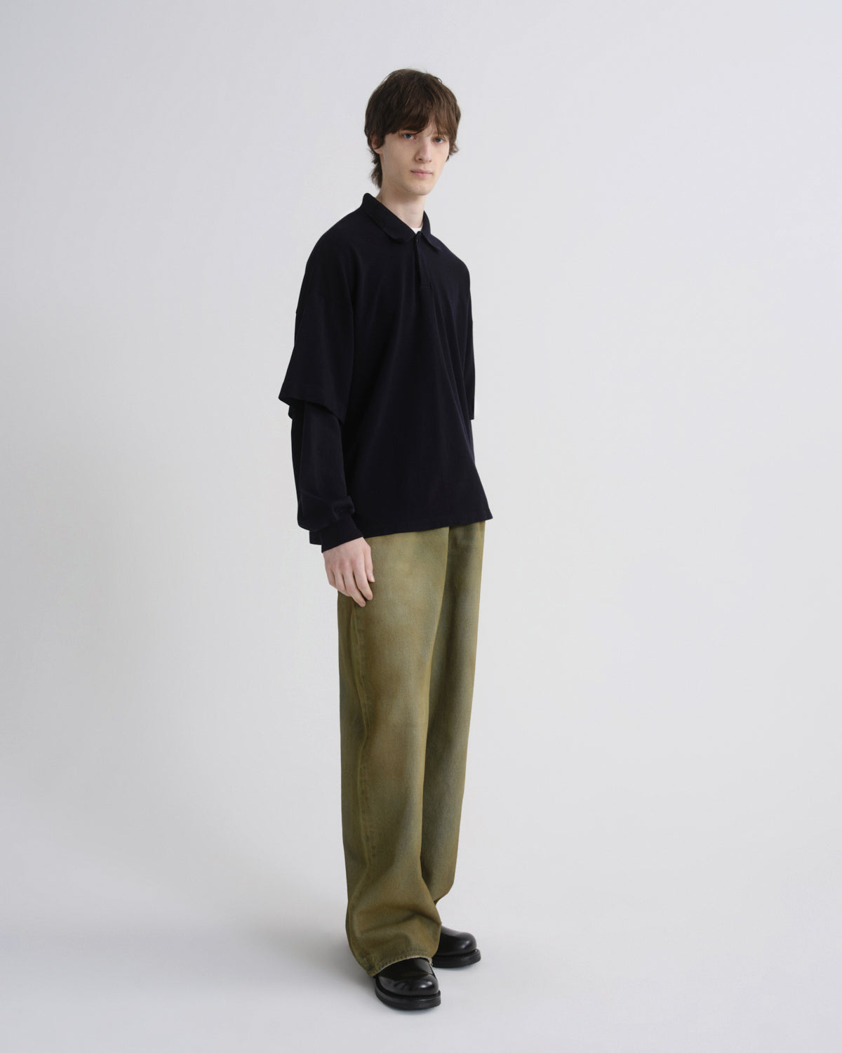 Person wearing a black shirt and green pants on a white background