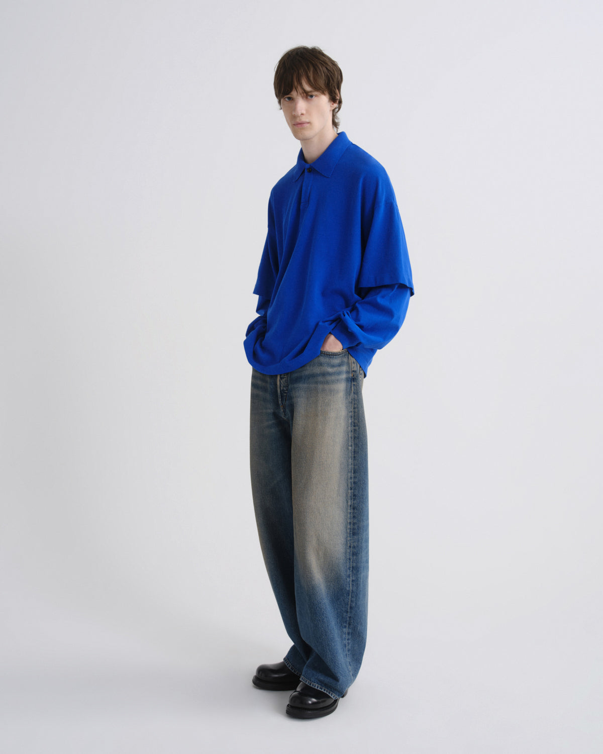 Person wearing a blue sweater and jeans on a white background