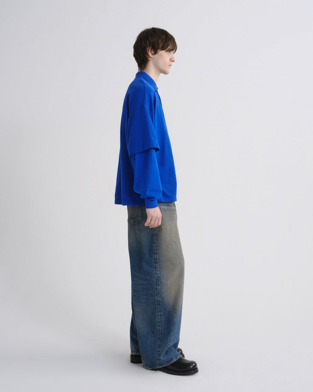 Person wearing a blue shirt and jeans on a white background