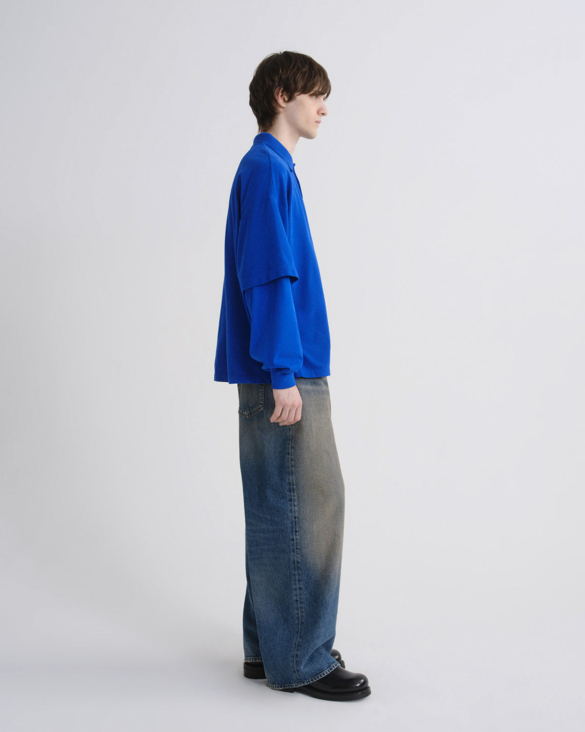 Person wearing a blue shirt and jeans on a white background