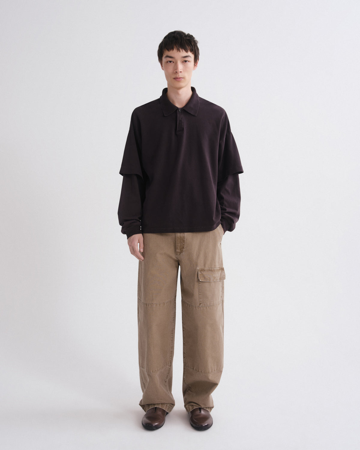 Person wearing a black shirt and brown pants on a white background