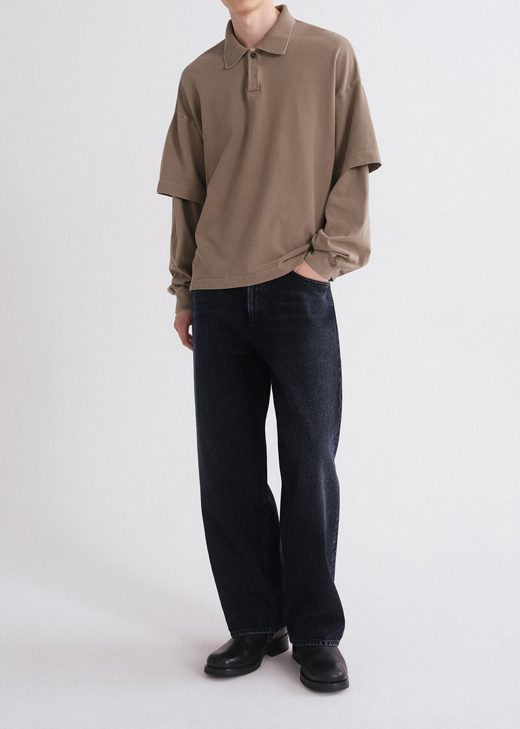 Person wearing a brown long-sleeve shirt and black pants on a white background