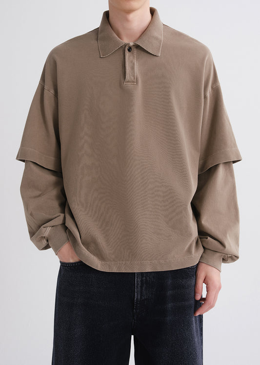 Person wearing a brown oversized shirt with a plain background