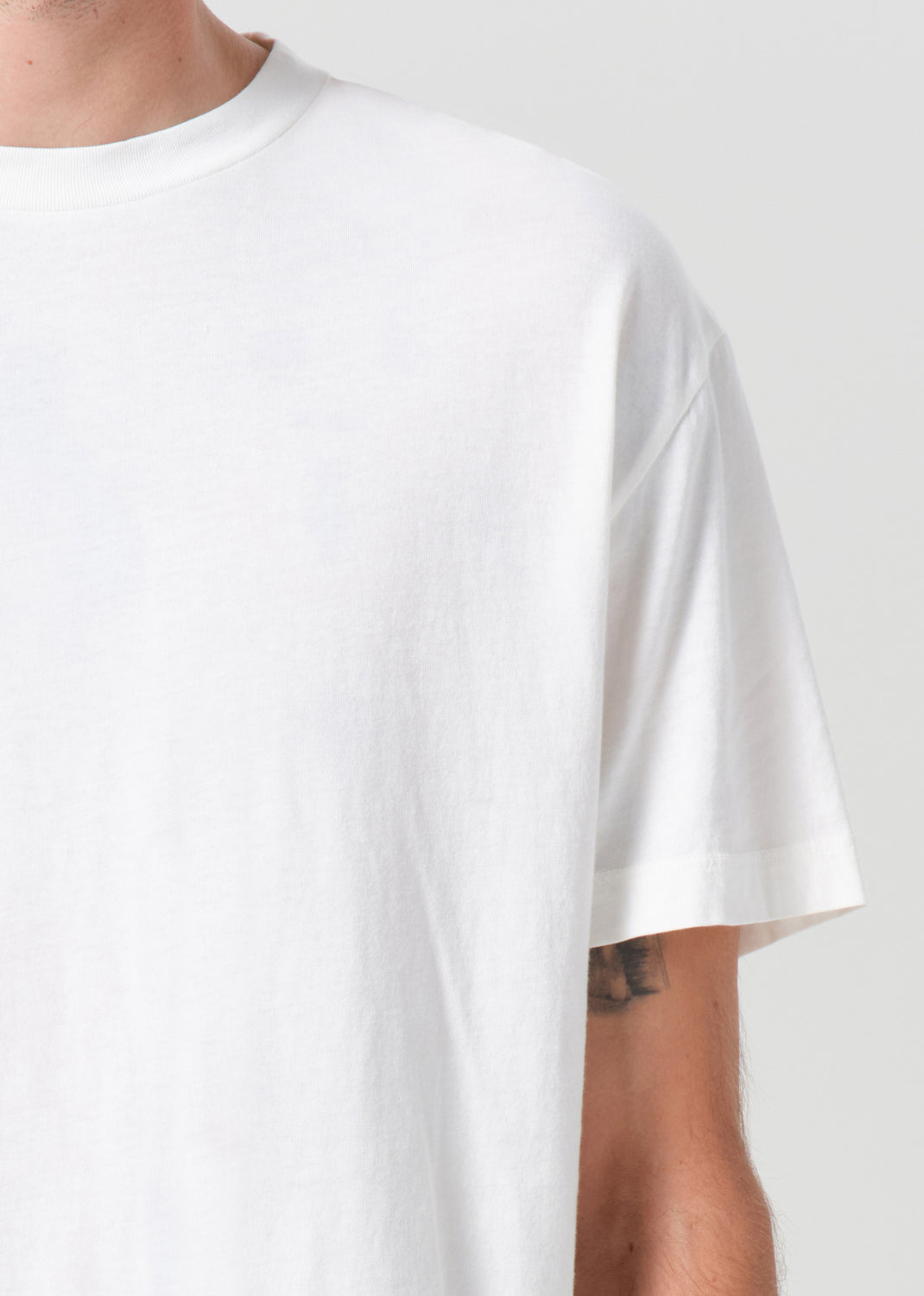 White t-shirt worn by a person on a plain background