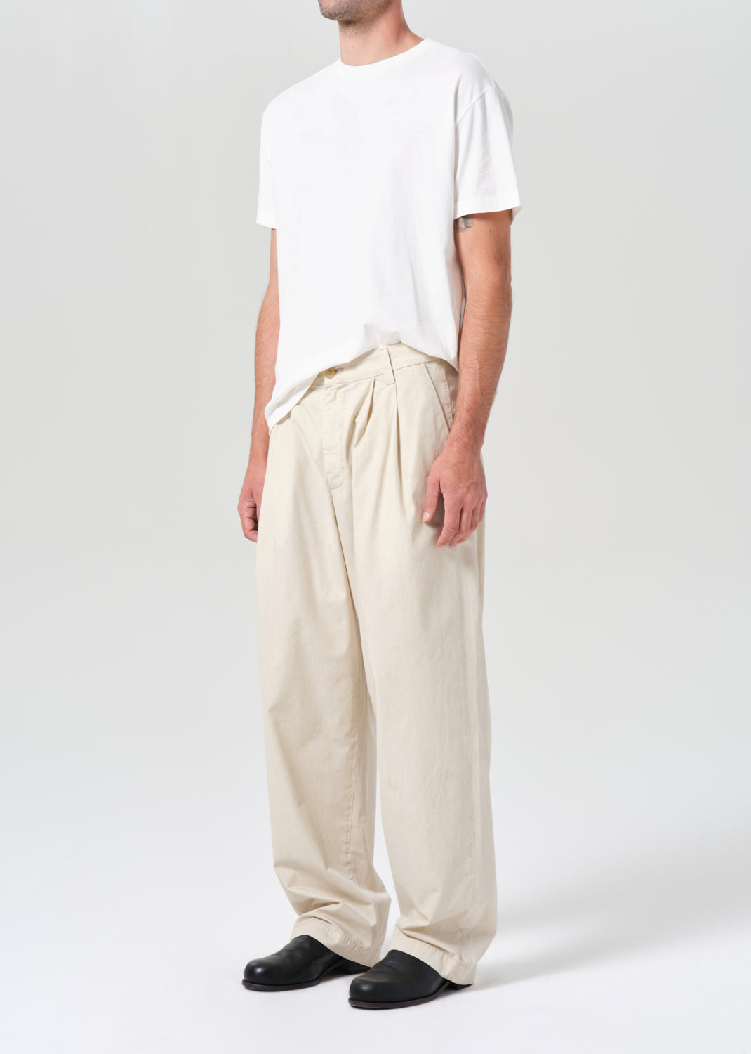 Person wearing a white t-shirt and beige wide-leg pants on a white background