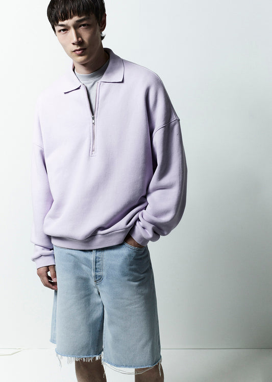 Person wearing a light purple sweatshirt and light blue shorts on a white background