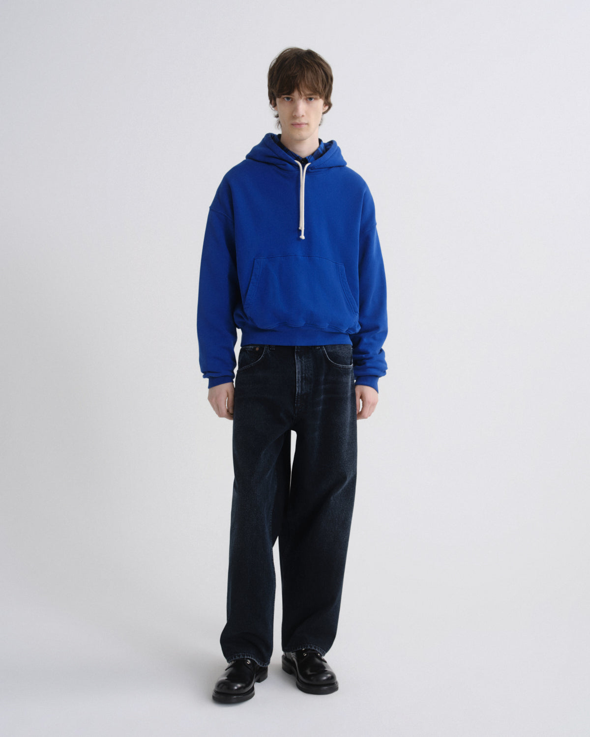 Person wearing a blue hoodie and black pants on a white background