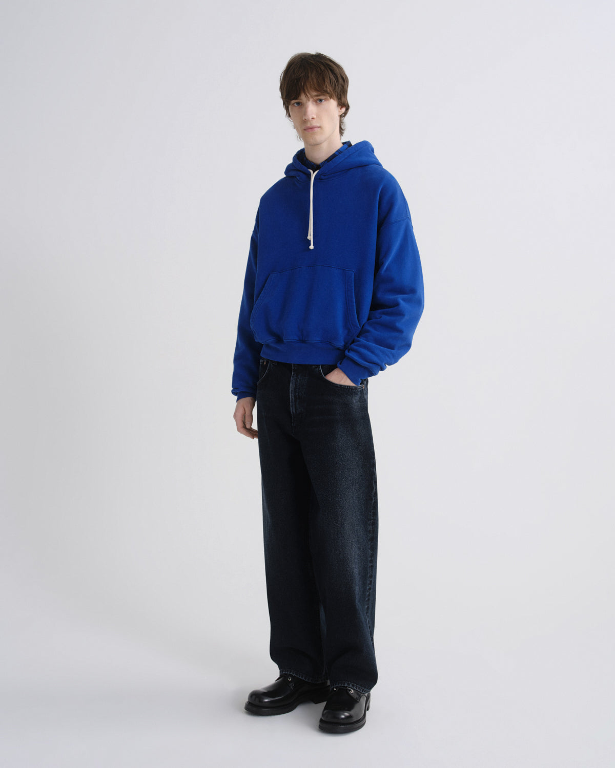 Person wearing a blue hoodie and black pants on a white background