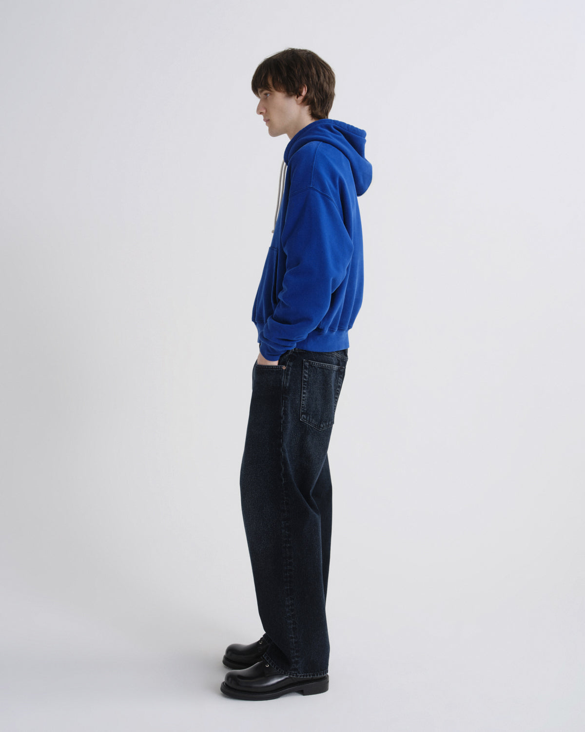 Person wearing a blue hoodie and black pants on a white background