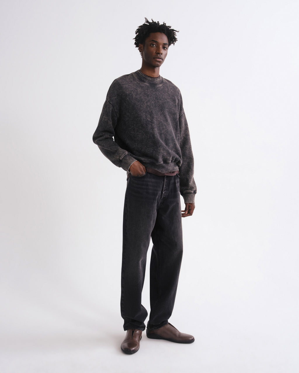 Man wearing a brown corduroy jumpsuit with embroidery on a white background