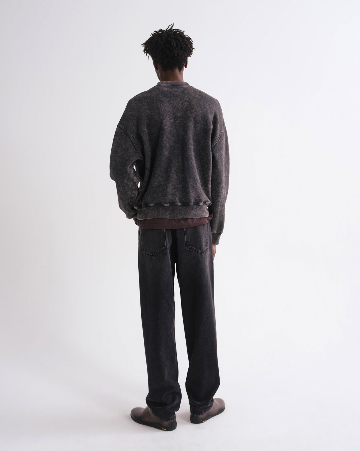 Person wearing a dark gray sweater and pants on a white background