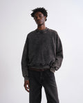 Person wearing a dark gray sweatshirt and black pants on a white background