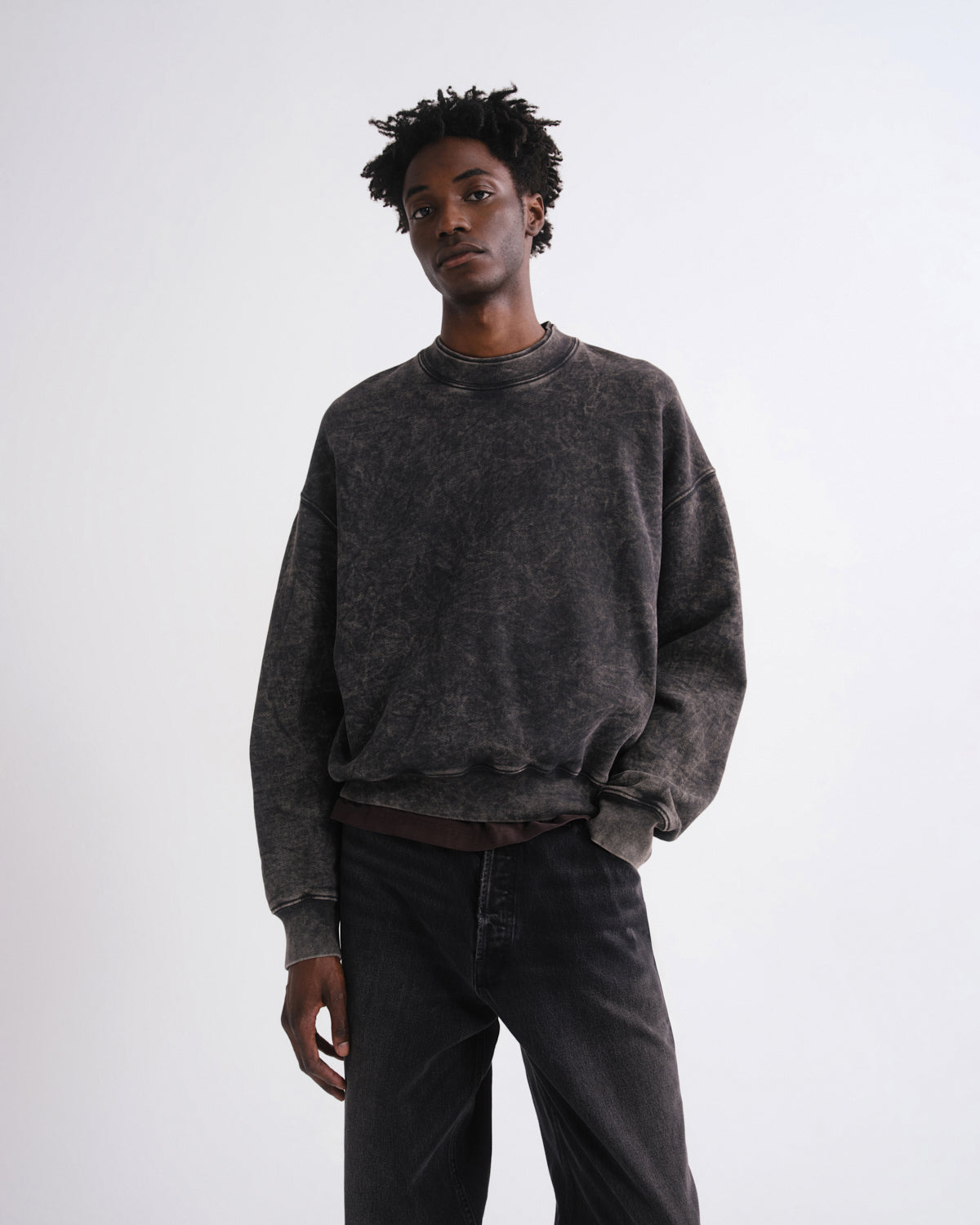 Person wearing a dark gray sweatshirt and black pants on a white background