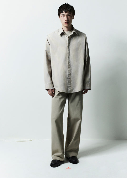 Person wearing a beige shirt and pants on a white background