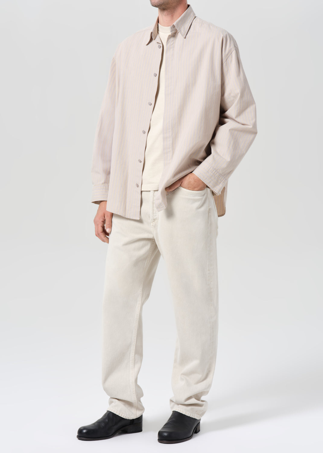 Person wearing a beige shirt and pants with a white background