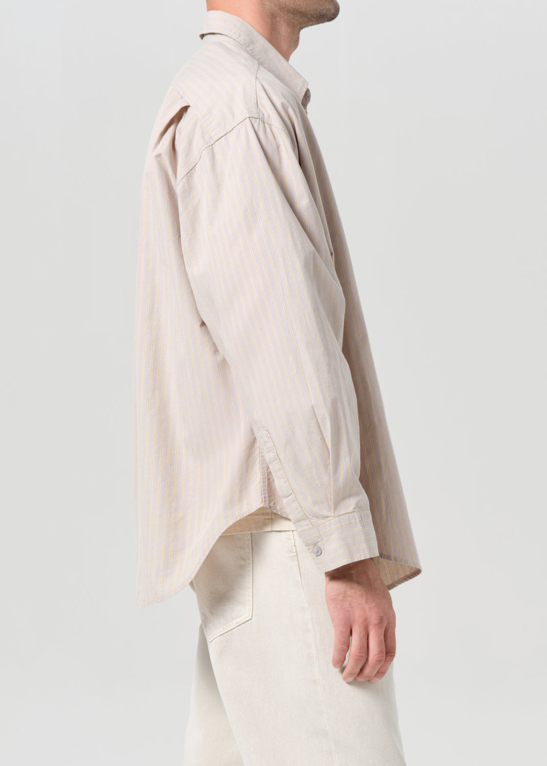 Person wearing a beige shirt and pants on a light gray background