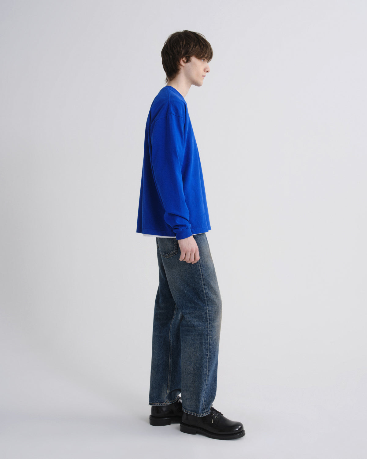 Person wearing a blue sweater and jeans on a grey background