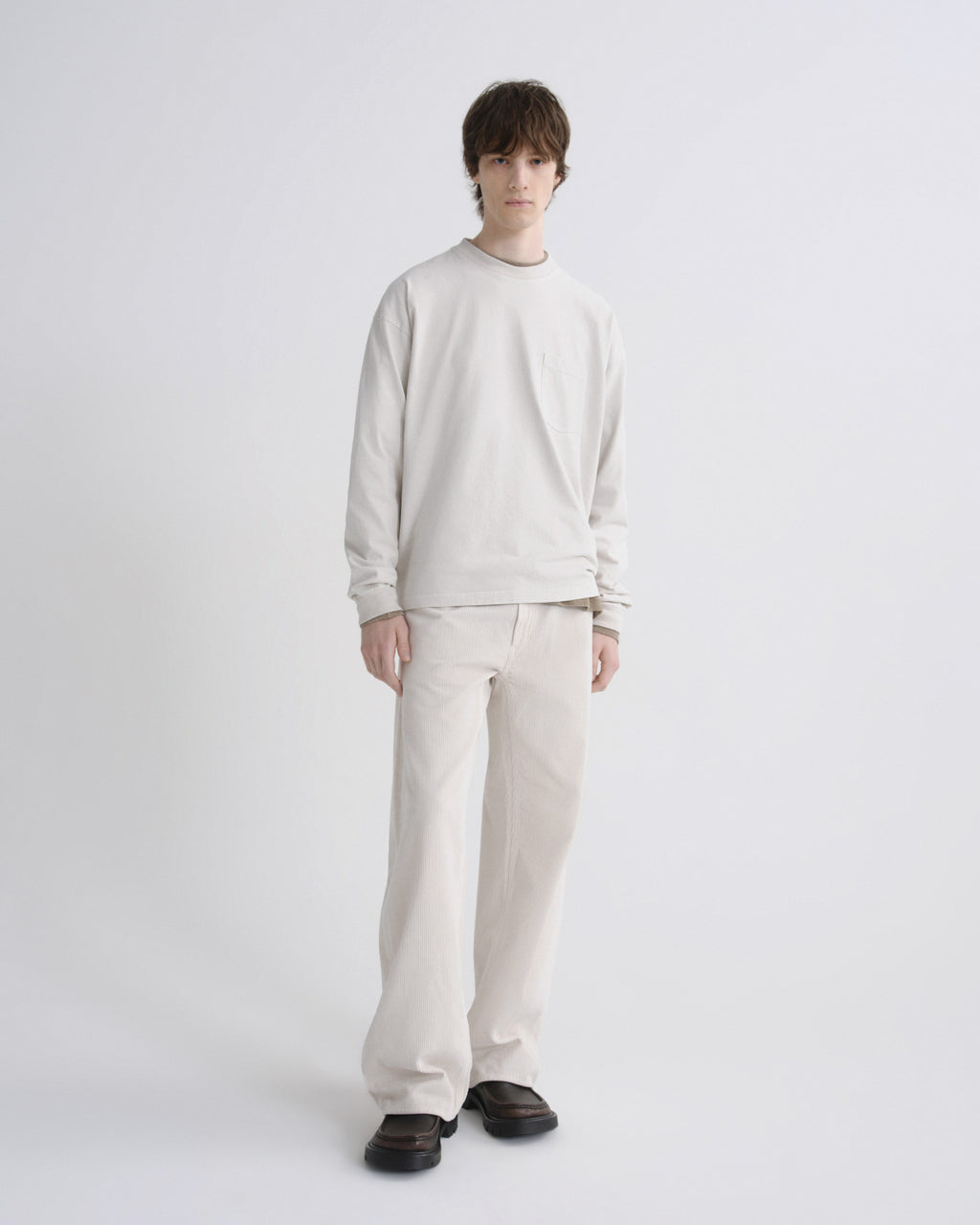 Person wearing a light gray sweater and pants on a white background