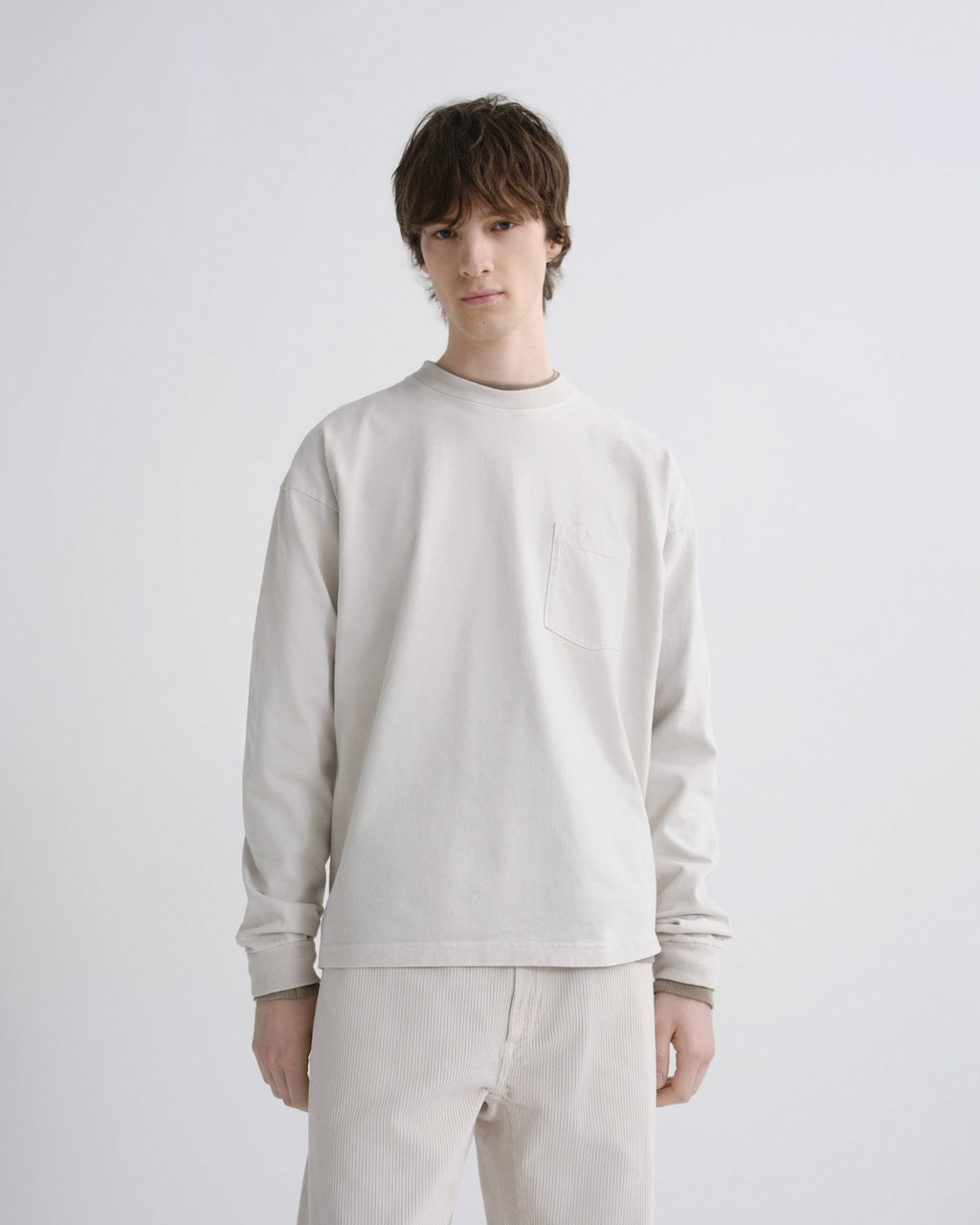 Person wearing a light gray sweatshirt and pants on a white background