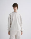 Person wearing a light gray sweatshirt and pants on a white background