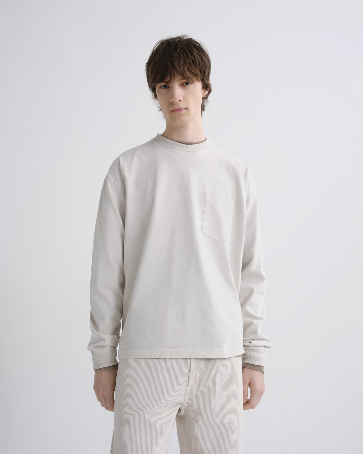 Person wearing a light gray sweatshirt and pants on a white background