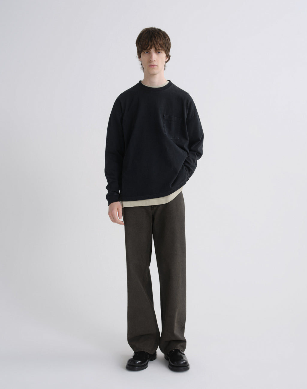 Person wearing a black sweater and gray pants on a white background