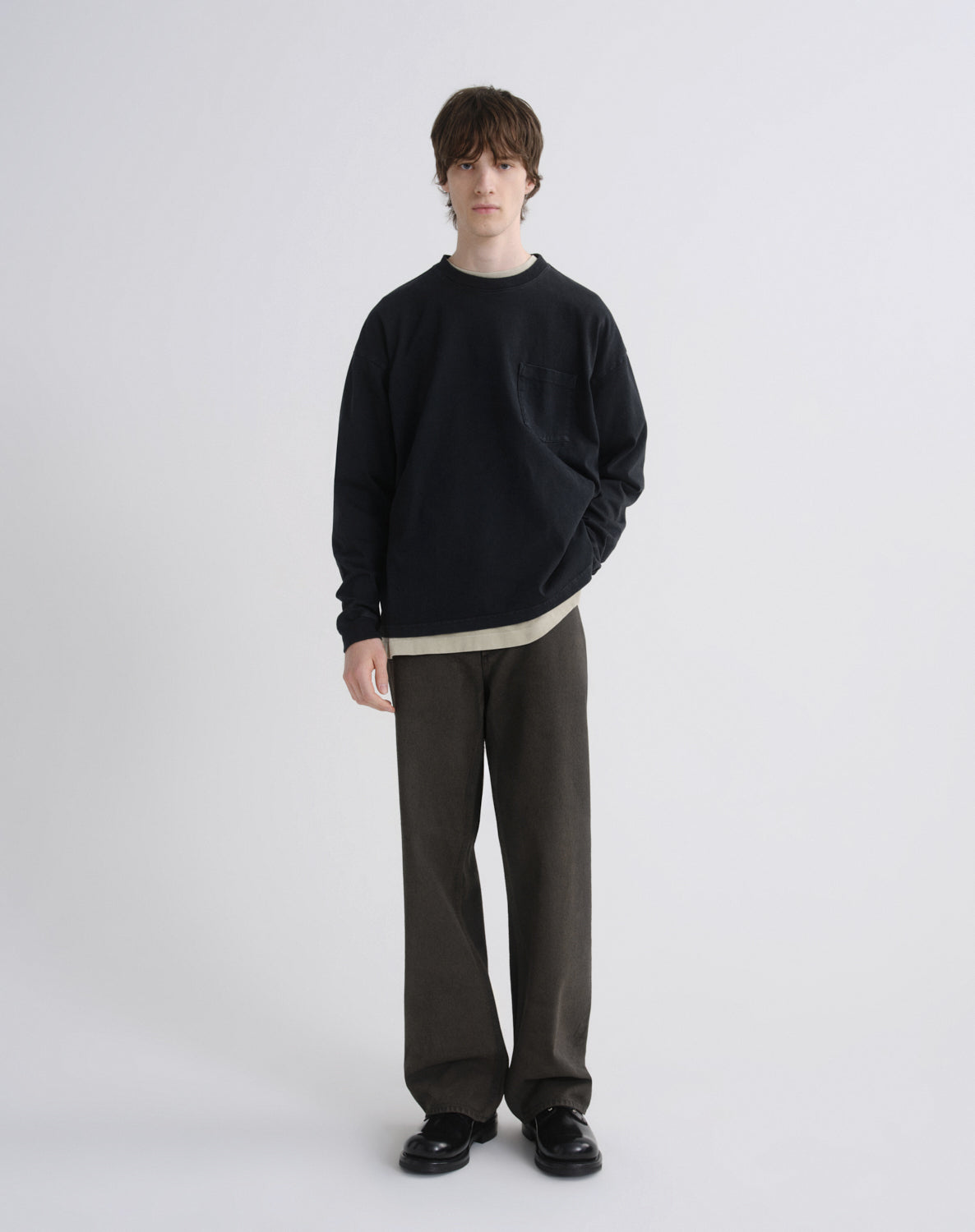 Person wearing a black sweater and gray pants on a white background