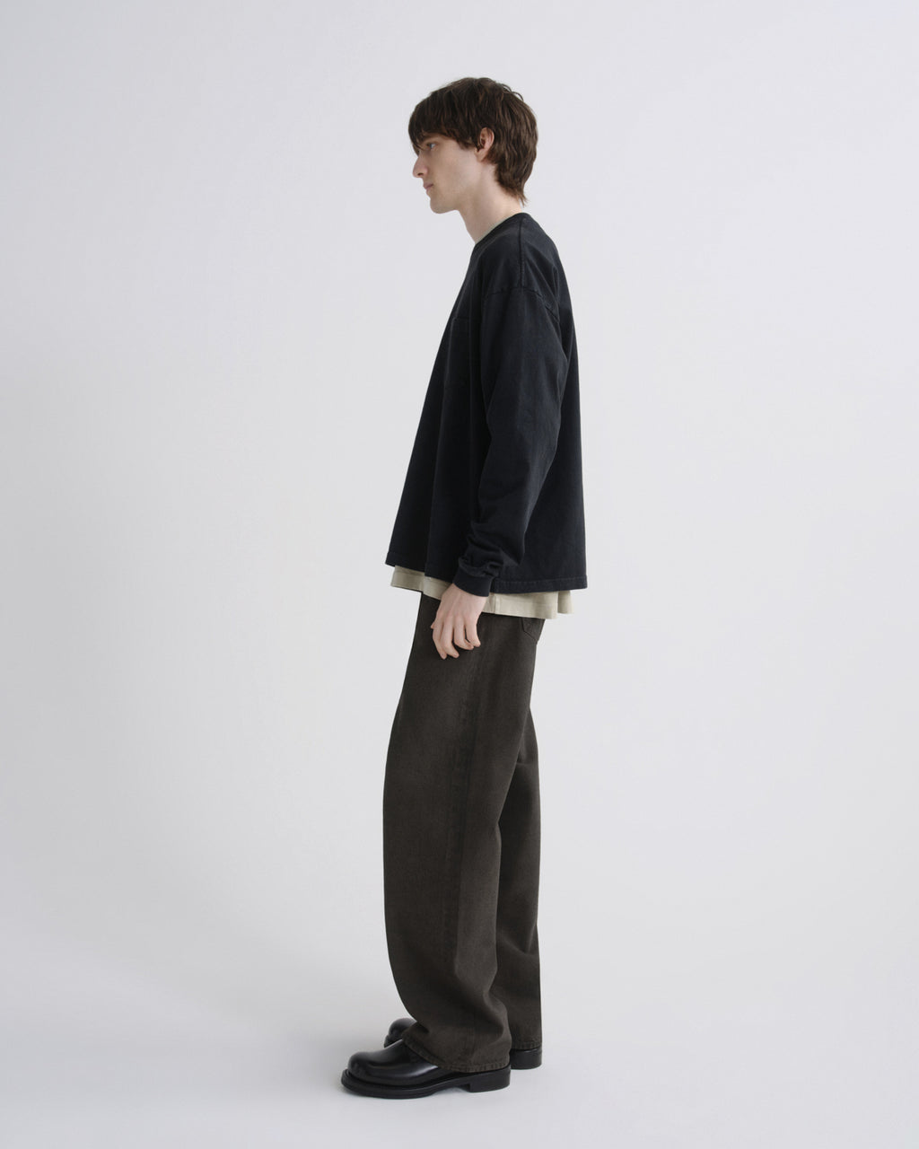 Person wearing a black jacket and dark pants on a white background