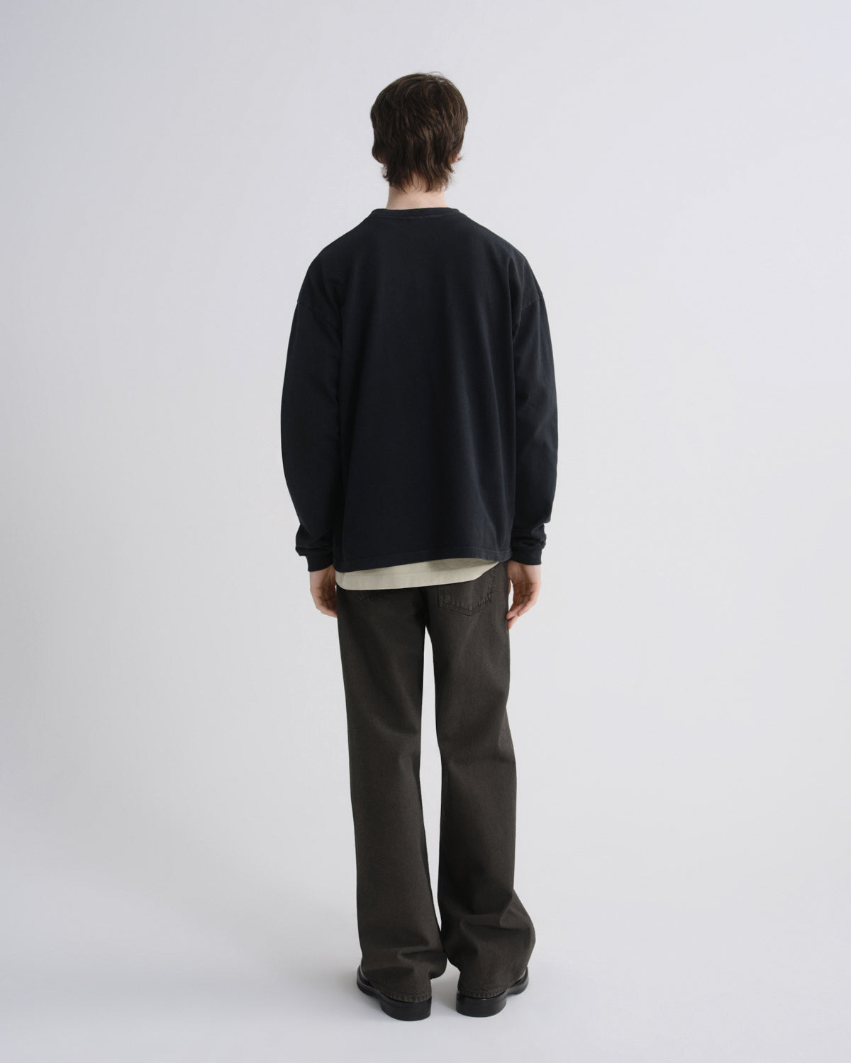 Person wearing a black sweater and dark pants on a white background