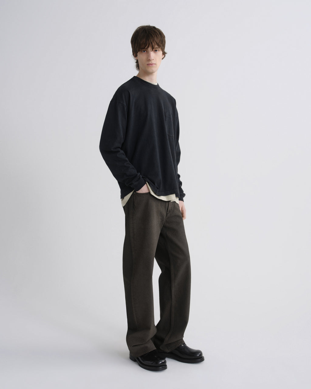 Person wearing a black sweater and dark pants on a white background