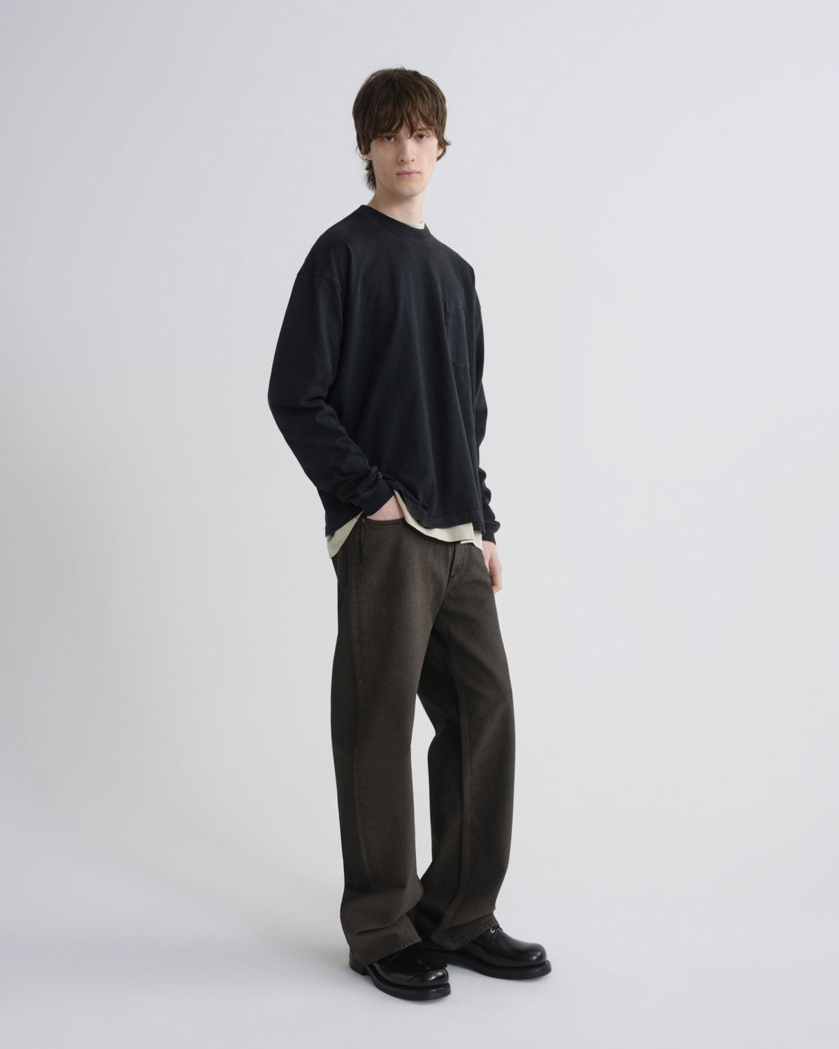 Person wearing a black sweater and dark pants on a white background