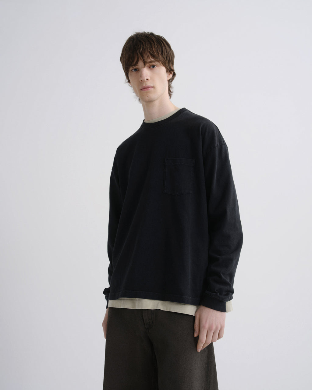 Person wearing a black sweater and brown pants on a white background