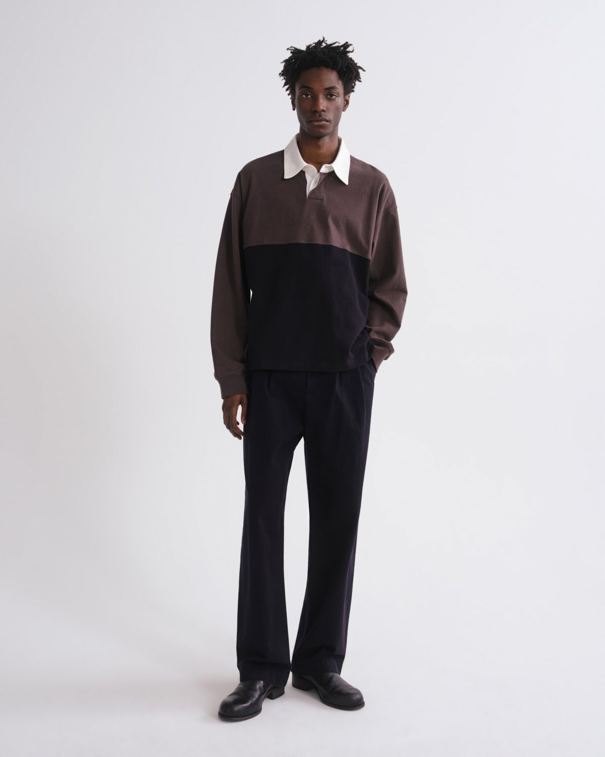 Person wearing a two-tone sweater and black pants on a grey background