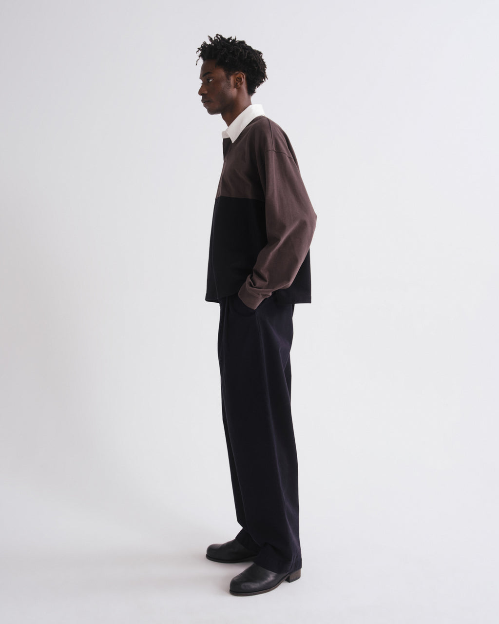 Person wearing a two-tone shirt and black pants on a grey background