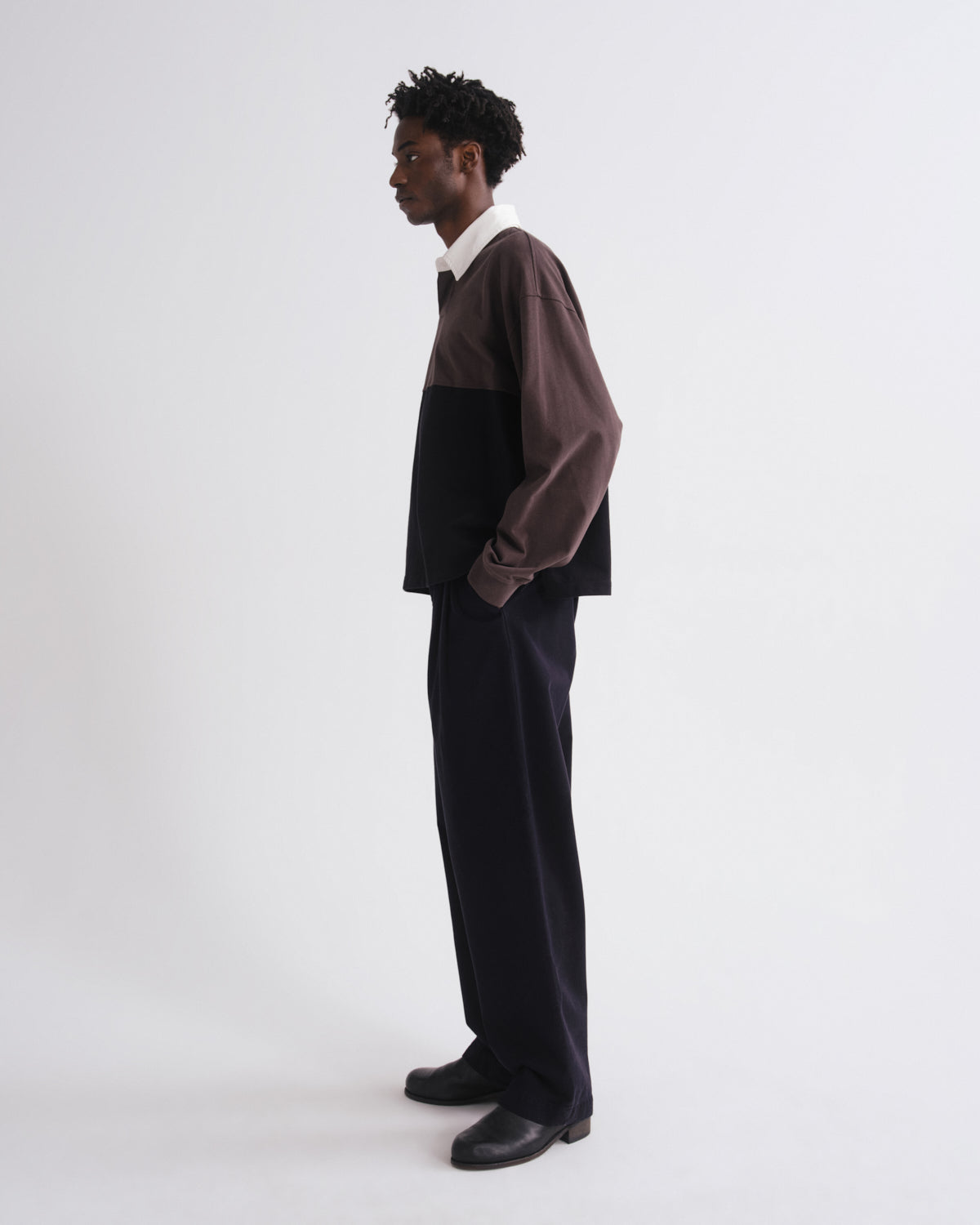 Person wearing a two-tone shirt and black pants on a grey background