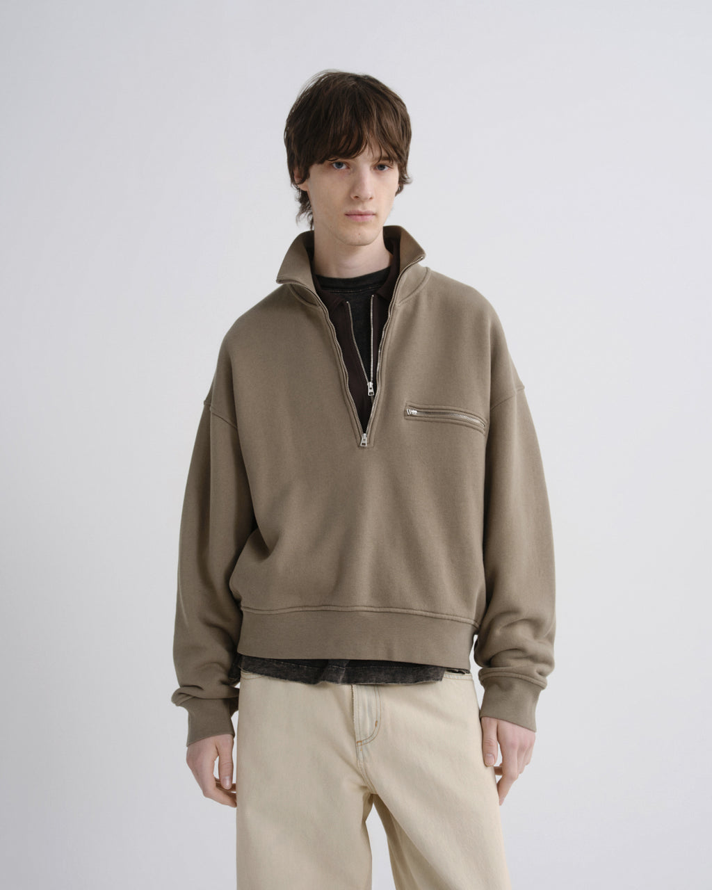 Person wearing a beige half-zip sweatshirt on a white background