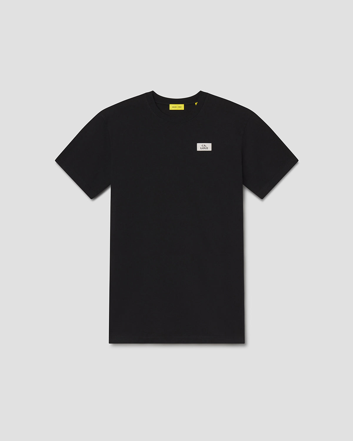 A black short-sleeve crewneck t-shirt with a small white rectangular logo patch on the left chest and a yellow neck label, displayed flat against a light gray background.