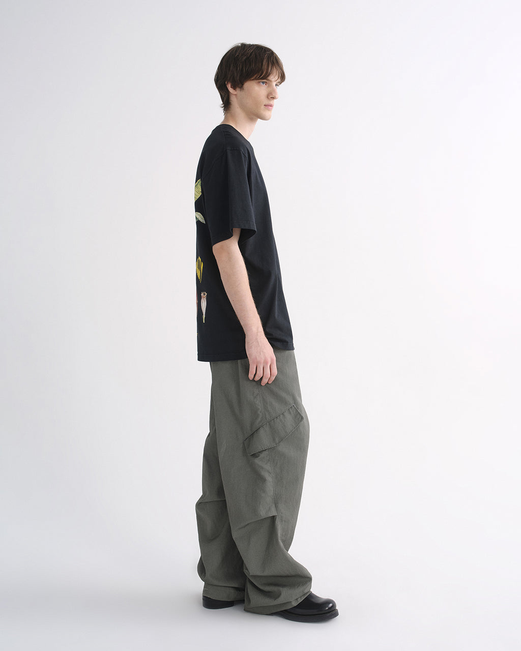 Person wearing black graphic T-shirt and grey cargo pants, side view