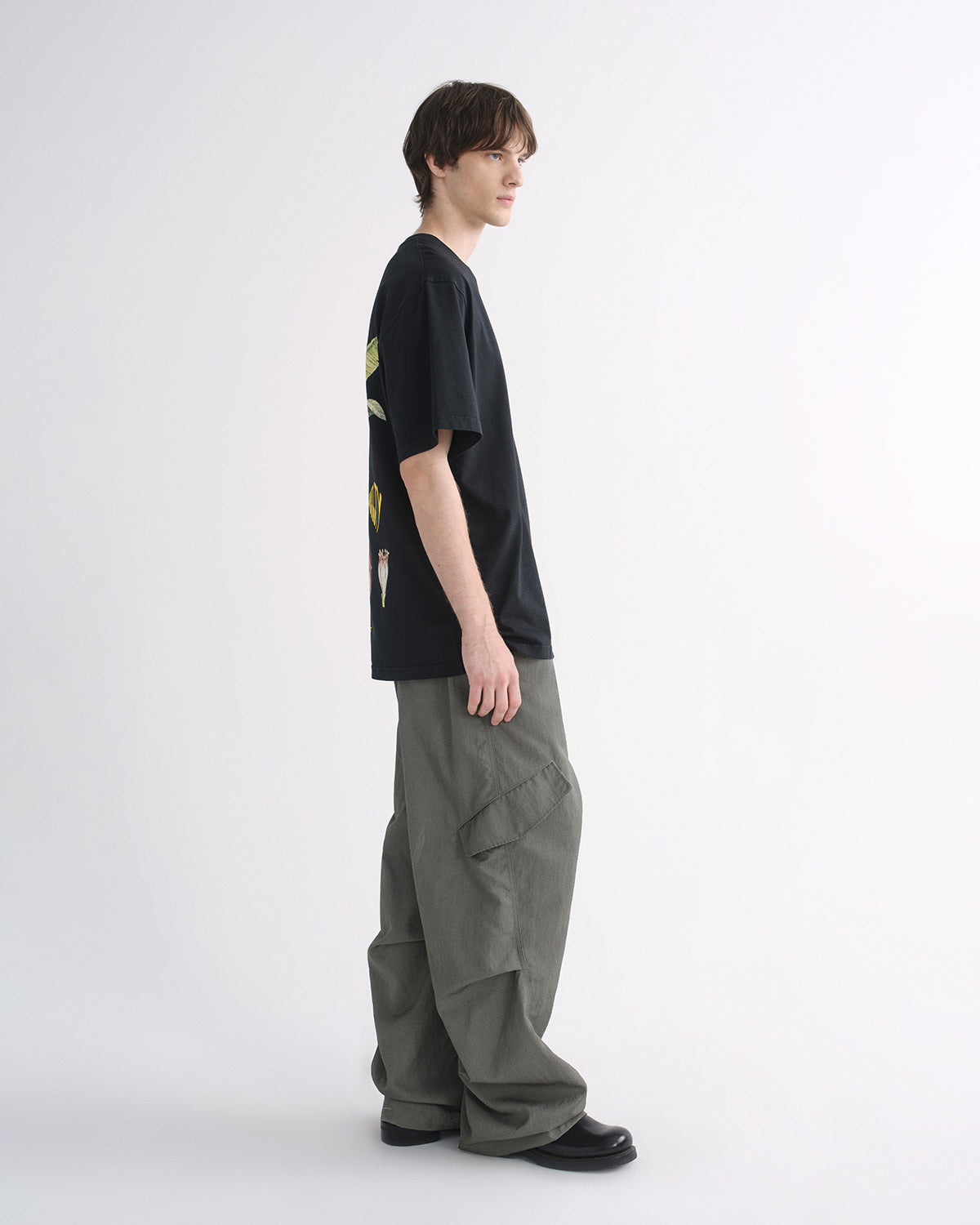 Person wearing black graphic T-shirt and grey cargo pants, side view